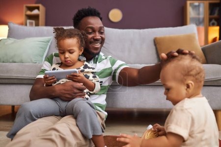 Photo for Portrait of happy Black father enjoying family time with two little children at home and smiling joyful - Royalty Free Image