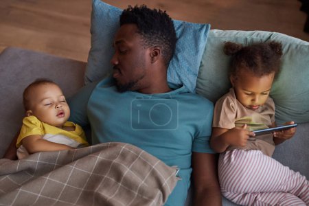 Photo for Top down view of Black father with two little kids lying in bed together at nap time - Royalty Free Image