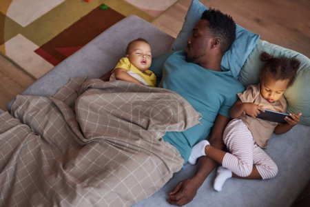 Photo for Top down view of exhausted Black father sleeping with two little kids at nap time - Royalty Free Image