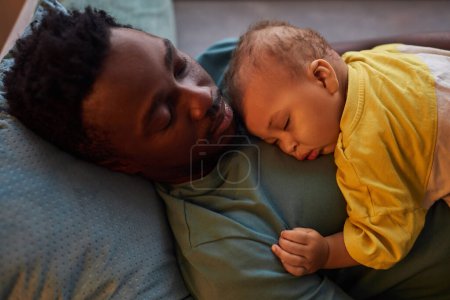 Photo for Candid portrait of young father and son falling asleep together at naptime - Royalty Free Image