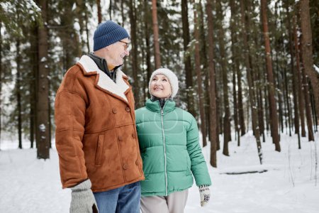 Foto de Mujer mayor feliz mirando al marido con amor y afecto cuando están caminando en el parque de invierno - Imagen libre de derechos