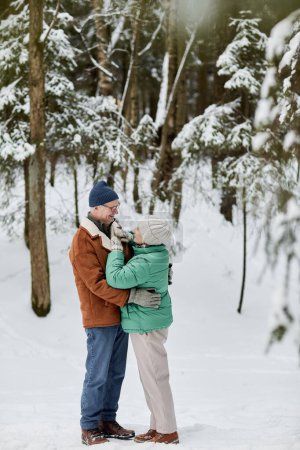 Senior man and woman in winter clothes hugging and look at each other
