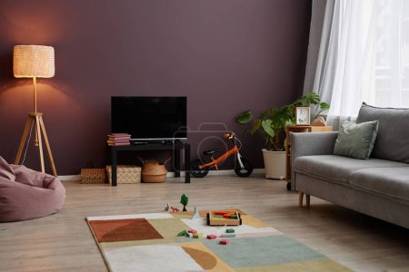 Foto de Imagen de fondo del acogedor interior de la sala de estar con pared marrón y juguetes para niños dispersos en la alfombra, espacio de copia - Imagen libre de derechos