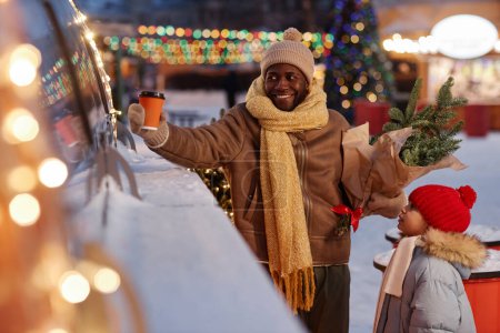 Téléchargez les photos : Portrait de père et fille heureux achetant des boissons au camion de nourriture dans le marché de Noël - en image libre de droit