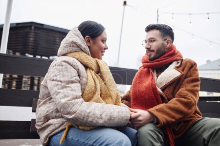 Téléchargez les photos : Portrait de jeune couple tenant la main en hiver à l'extérieur et se regardant en souriant - en image libre de droit