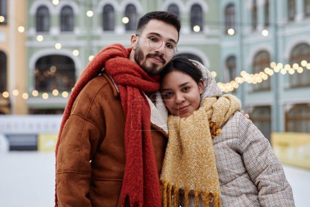 Foto de Retrato de la cintura hacia arriba de la pareja joven mirando la cámara al aire libre en el entorno de la ciudad de invierno - Imagen libre de derechos