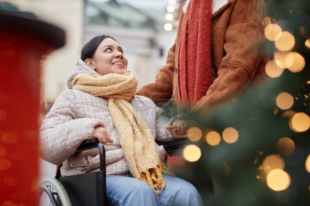 Foto de Retrato de mujer joven con discapacidad mirando a su pareja sonriendo en el mercado de Navidad, espacio para copiar - Imagen libre de derechos