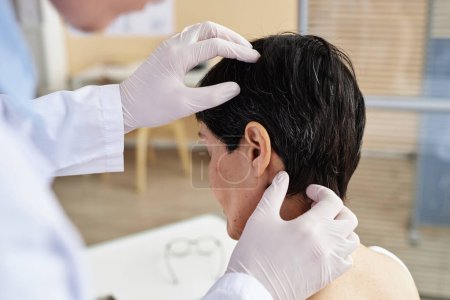 Foto de Primer plano del médico que sostiene la cabeza y el cuero cabelludo de la paciente femenina en la clínica de dermatología, espacio de copia - Imagen libre de derechos