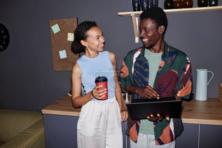 Porträt zweier lächelnder schwarzer junger Leute, die an der Kaffeestation in der Bürolounge stehen