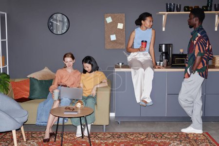Diverse group of Gen Z young people relaxing in office lounge with flash