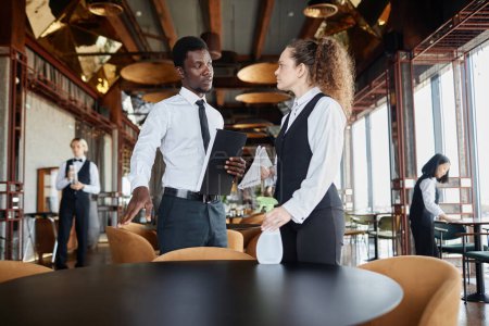 Tailliertes Porträt des schwarzen Mannes als Manager Schulung Server Reinigung Speisesaal in Luxusrestaurant, Kopierraum