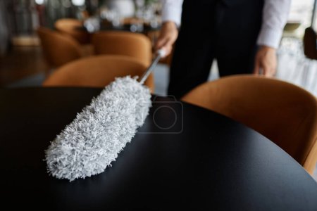 Téléchargez les photos : Gros plan des tables à manger essuyant l'eau avec plumeau dans le cadre de la salle à manger de luxe, espace de copie - en image libre de droit