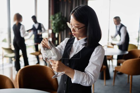 Téléchargez les photos : Portrait taille haute de la jeune femme asiatique comme des lunettes de polissage serveur classique dans un restaurant de luxe, espace de copie - en image libre de droit