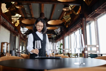 Téléchargez les photos : Portrait de femme asiatique élégante comme tables de réglage de serveur féminin dans un restaurant de luxe préparant pour les invités, espace de copie - en image libre de droit