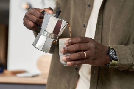 Primer plano de hombre negro irreconocible haciendo taza de delicioso café en casa y verter bebida en la taza, espacio de copia