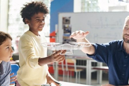 Photo for Physics teacher explaining kid how propellers of quadcopter works - Royalty Free Image