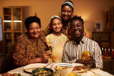 Foto de Feliz abuela, nieta y padres reunidos en la mesa de la cena Kwanzaa - Imagen libre de derechos