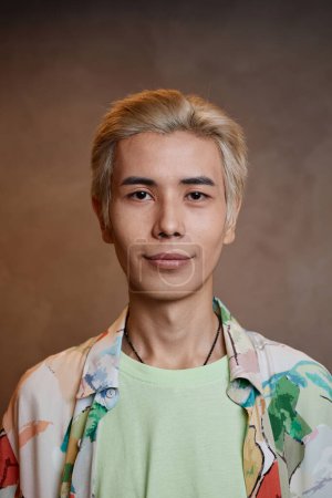 Vertikale Nahaufnahme Porträt eines jungen asiatischen Mannes mit gebleichten Haaren, der im Studio in die Kamera schaut