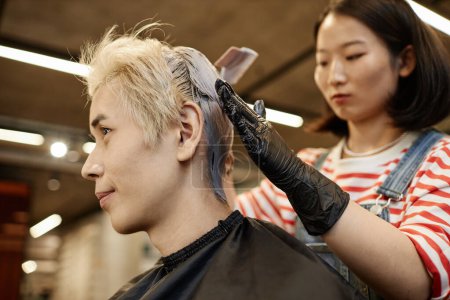 Seitenansicht Porträt eines jungen asiatischen Mannes im Schönheitssalon mit Friseur Bleichen oder Färben der Haare