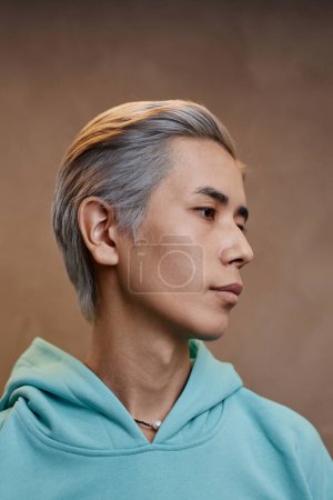 Seitenansicht Nahaufnahme Porträt eines jungen asiatischen Mannes mit moderner Herrenfrisur posiert vor neutralem Hintergrund im Studio