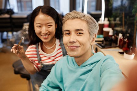 POV von lächelnden asiatischen Mann Selfie in Schönheitssalon mit Friseur