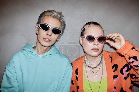Retrato de dos parejas jóvenes creativas con gafas de sol y posando con flash