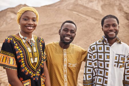 Grupo de jóvenes afroamericanos vestidos con ropa tradicional en el desierto, todos sonriendo