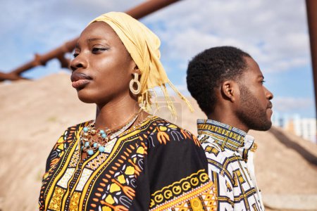 Primer plano retrato de pareja afroamericana tradicional de pie espalda con espalda en el sol del desierto, se centran en la mujer en primer plano