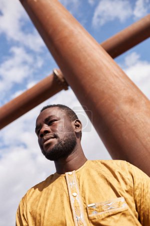 At angle shot of African American man looking away against sky with geometric shape
