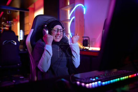 Photo for Portrait of joyful Middle Eastern young woman celebrating win while playing video game in cybersports club, copy space - Royalty Free Image