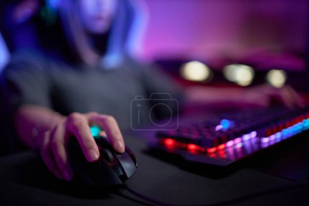 Photo for Close up of female hand holding computer mouse in cybersports club with neon lights, copy space - Royalty Free Image