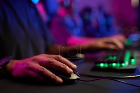 Photo for Close up of unrecognizable person playing videogames in neon light with focus on hand holding computer mouse, copy space - Royalty Free Image