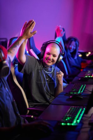 Photo for Vertical portrait of gen Z young woman playing video games professionally and high five teammate in eSports competition - Royalty Free Image