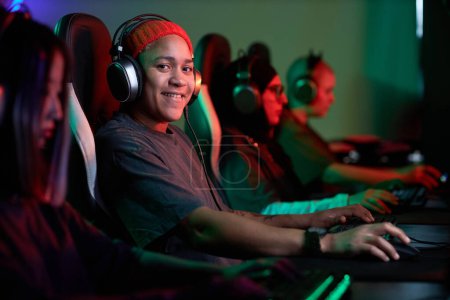 Photo for Portrait of African American woman playing video games and smiling at camera with pro cybersports team, copy space - Royalty Free Image