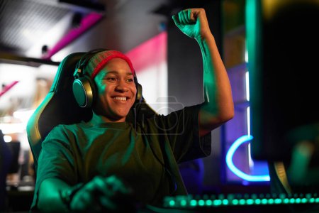 Photo for Portrait of smiling African American woman as gamer celebrating victory in neon lighting, copy space - Royalty Free Image