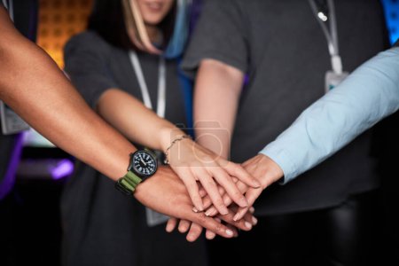 Photo for Close up of multiethnic female team stacking hands and celebrating victory on stage during competitive eSports event - Royalty Free Image