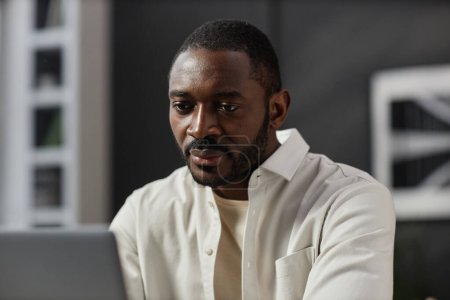 Photo for Portrait of adult African American man looking at laptop screen while working at home office, copy space - Royalty Free Image