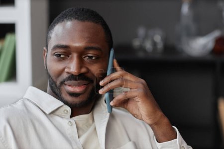 Photo for Close up portrait of adult African American man speaking by phone at home with smile, copy space - Royalty Free Image