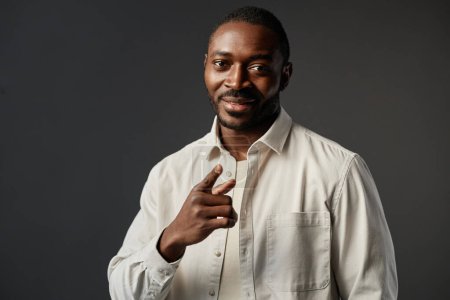 Photo for Waist up portrait of confident African American man smiling at camera and pointing, copy space - Royalty Free Image