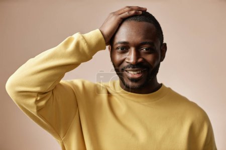 Photo for Minimal portrait of adult Black man looking at camera in studio with hand on hair - Royalty Free Image