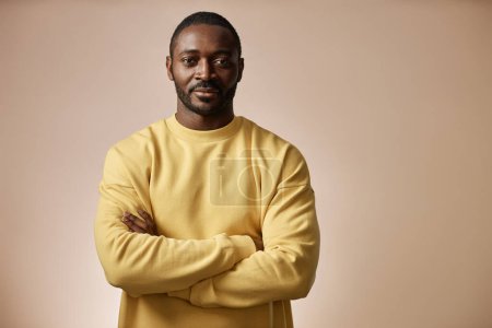 Photo for Minimal portrait of confident Black man looking at camera in studio standing with arms crossed against neutral background, copy space - Royalty Free Image