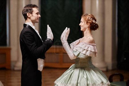 Seitenansicht Porträt eines jungen Herren und einer jungen Dame, die zusammen im Ballsaal des Palastes tanzen, mit einem Lächeln, Kopierraum