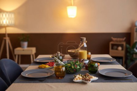 Hintergrundbild eines eleganten Esstisches mit Tellern und Geschirr in gemütlichem Kopierraum bei wenig Licht