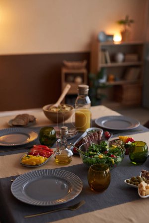 Vertikales Hintergrundbild eines eleganten Esstisches mit Tellern und Lebensmitteln bei wenig Licht