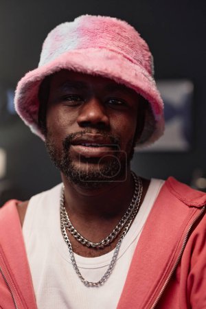 Vertical closeup portrait of African American man wearing pink hip-hop outfit looking at camera with dramatic lighting