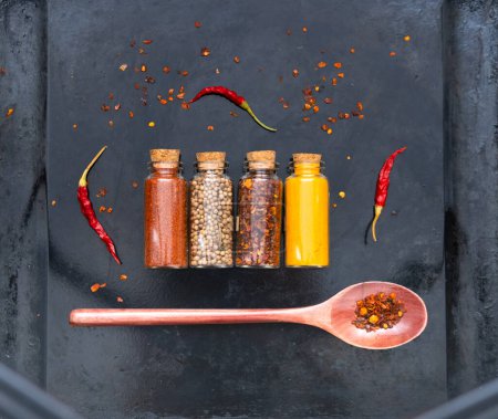 Photo for Spices and Provence herbs in glass containers on dark background. Atmospheric mood of the Year 2023. Close-up - Royalty Free Image