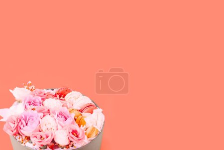 Photo for Rosebuds and multicolored macaroons for Valentines Day or Mothers Day on apricot crush background. National Pink Day.Template mock up of greeting card or text design. Bold hues for seasonal projects. - Royalty Free Image