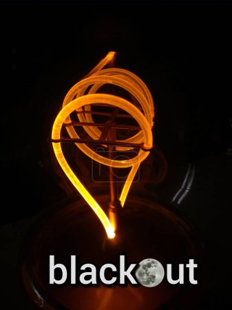 The inscription blackout on the background of a spiral light bulb on a dark background