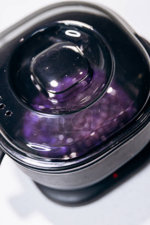 Purple granules are heated in black wax melter. Eyebrow tools