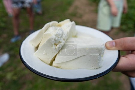 Téléchargez les photos : Hutsul fermier propose du fromage de brebis fraîchement préparé pour la dégustation pour les touristes ukrainiens à la fromagerie montagneuse des Carpates, Ukraine occidentale, Europe, gros plan - en image libre de droit